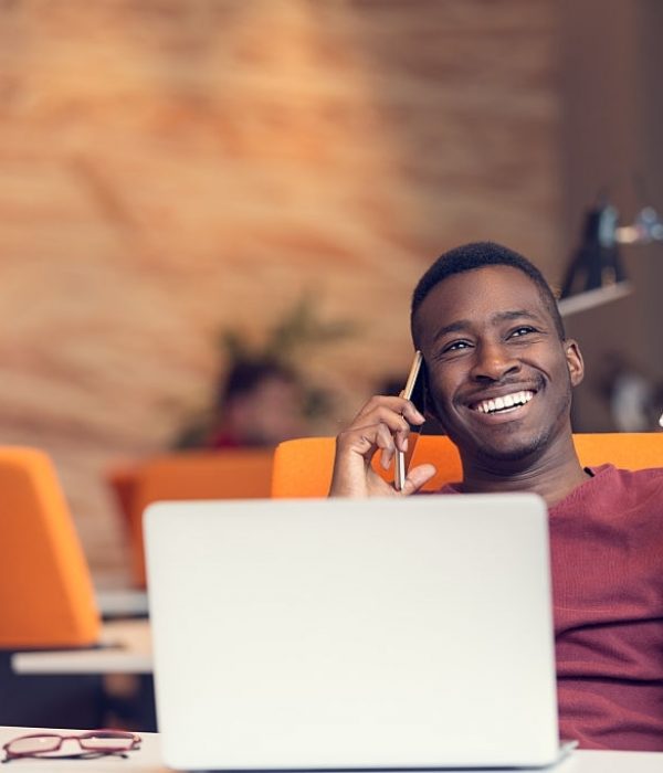 African American businessman on the phone sitting at the computer in his startup office